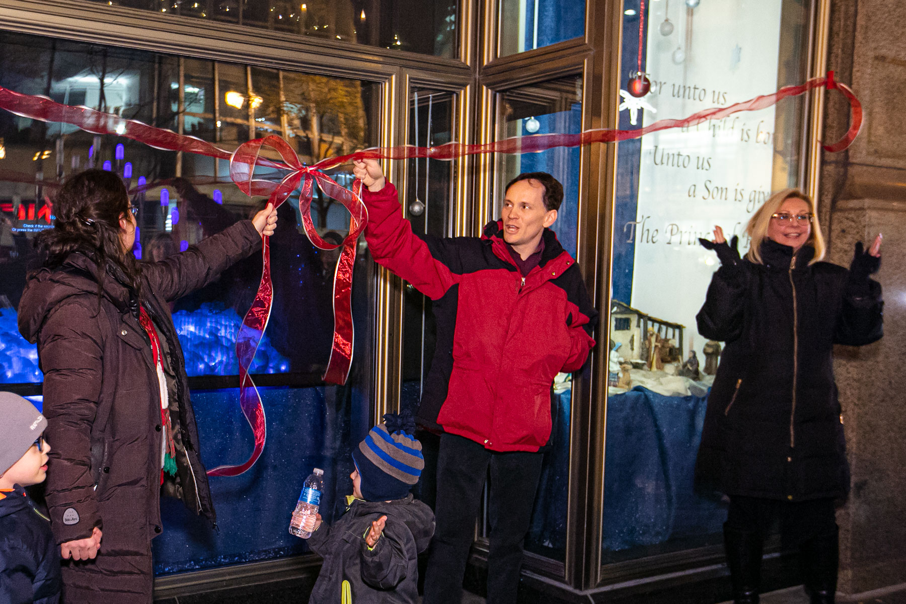 Left to right, Meghann Artes, Devin Bell and JoAnne Zielinski unveil the “Merry Christmas from DePaul” film and window display. A new tradition for DePaul, the display builds on the history of magical holiday windows along State Street for more than 100 years. (DePaul University/Randall Spriggs)